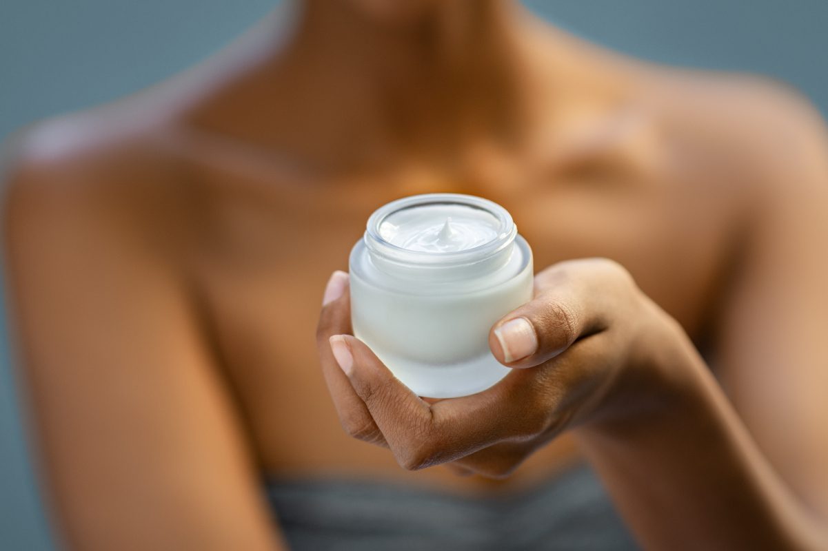 Beauty moisturizer for face treatment closeup Closeup of african woman holding moisturizer cream jar. Detail of black hands holding face lotion. Woman showing white moisturiser for healthy skin.